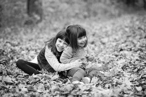 Sisters hugging in leaves black and white picture