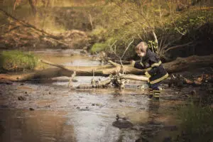 Perfectly captured photo of a boy playing in the river dressed as a fireman.