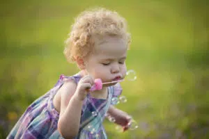 Kid Picture of girl with curly hair blowing bubbles