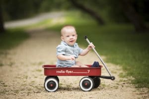 Photographers picture of happy boy in radio flyer red wagon.