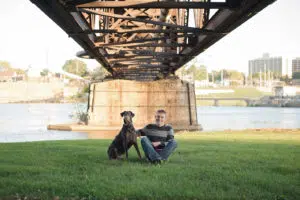 Graduate with his dog under a bridge during senior photos session