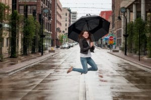 Girl jumping with umbrella in downtown Rockford during senior photos