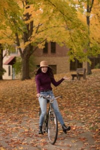 Girl with hat riding bike and laughing during photo shoot.