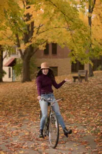 Girl with hat riding bike and laughing during photo shoot.